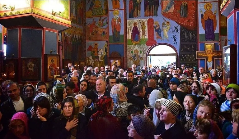 many smiling and dancing people in Slavic Church looling like colorful discoteque inside