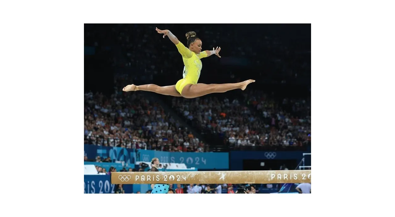 a gymnast in a yellow leotard doing a performace on a beam