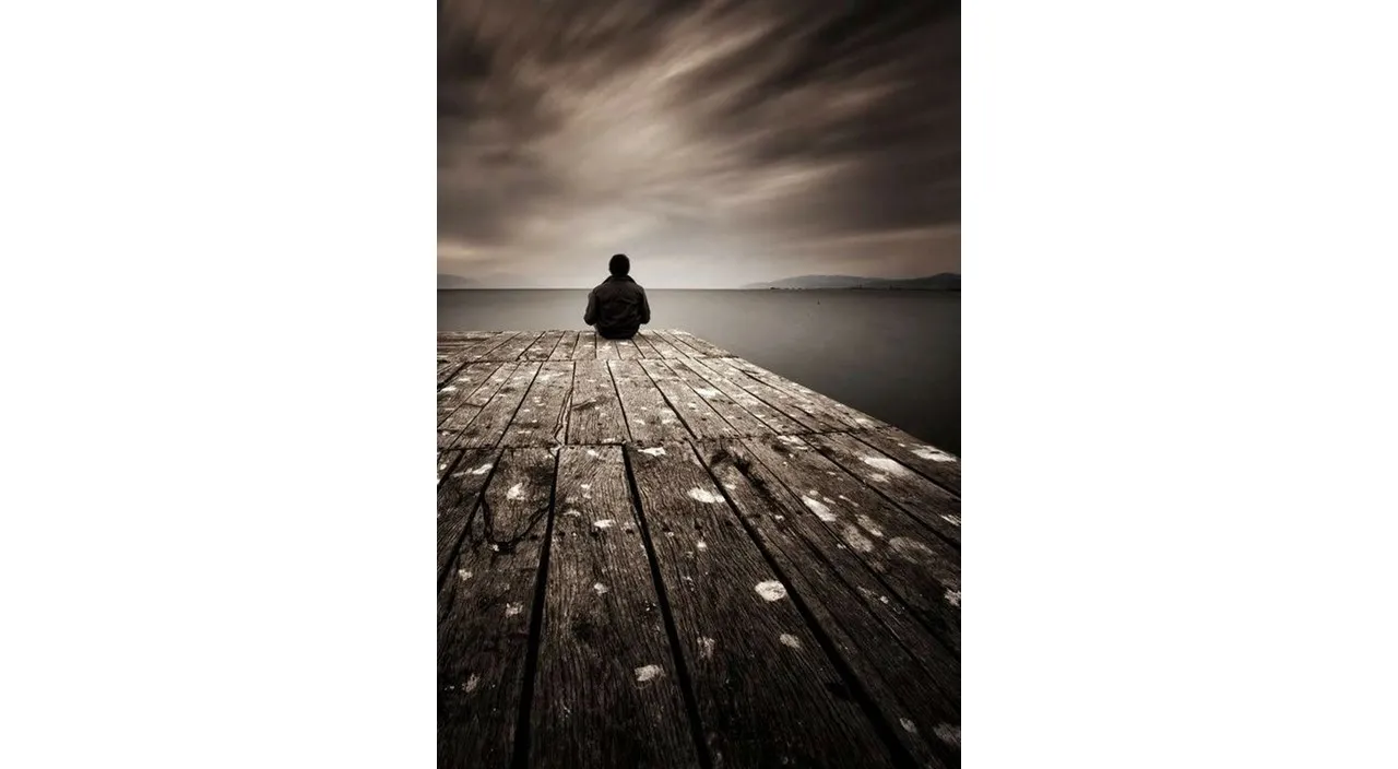 a person sitting on a dock looking out at the water