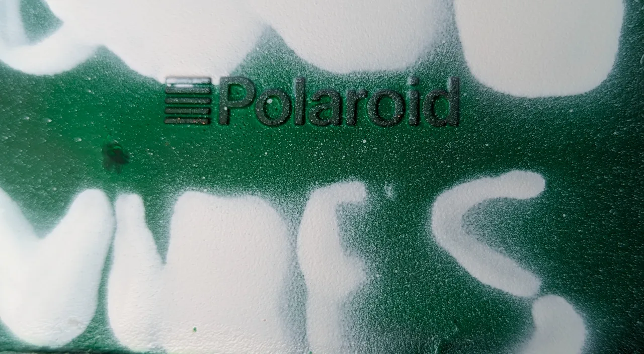 a green and white wall with the word polaroid painted on it