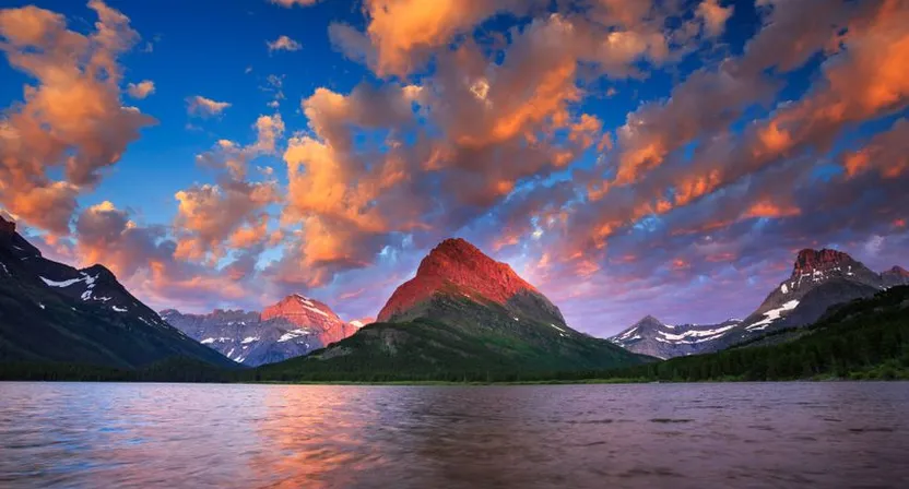 a beautiful sunset over a lake with mountains in the background