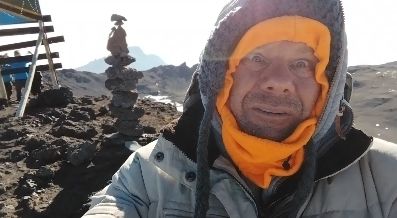 a man with a yellow scarf on his head taking a selfie