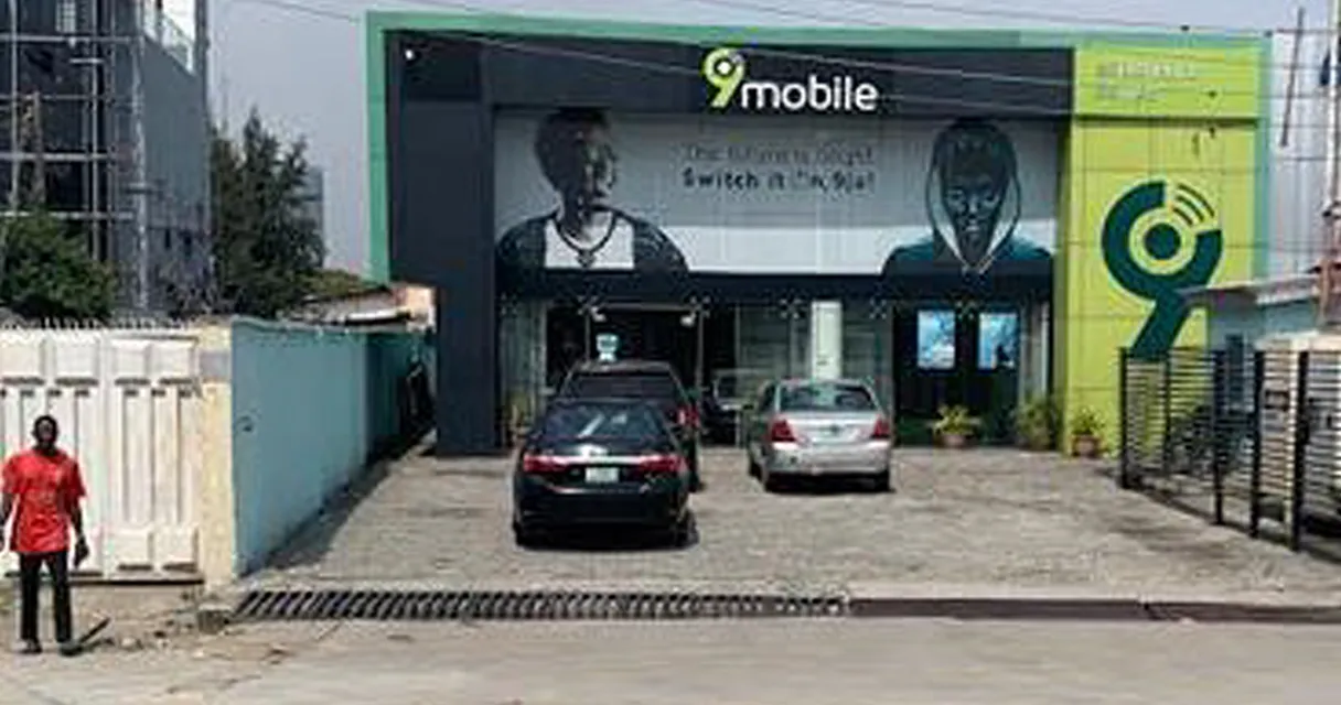 a man standing in front of a building with cars parked in front of it