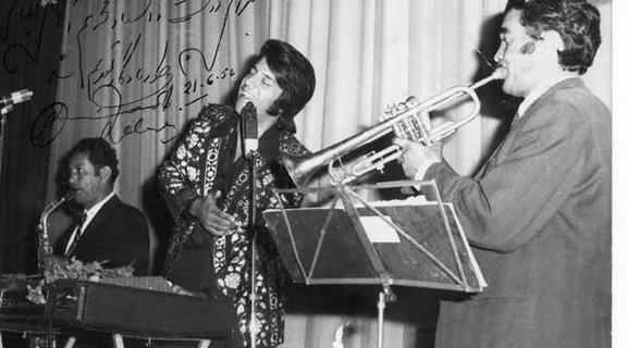 a woman playing a trumpet while standing next to a man