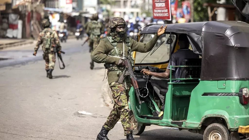 a man in camouflage walking next to a green vehicle