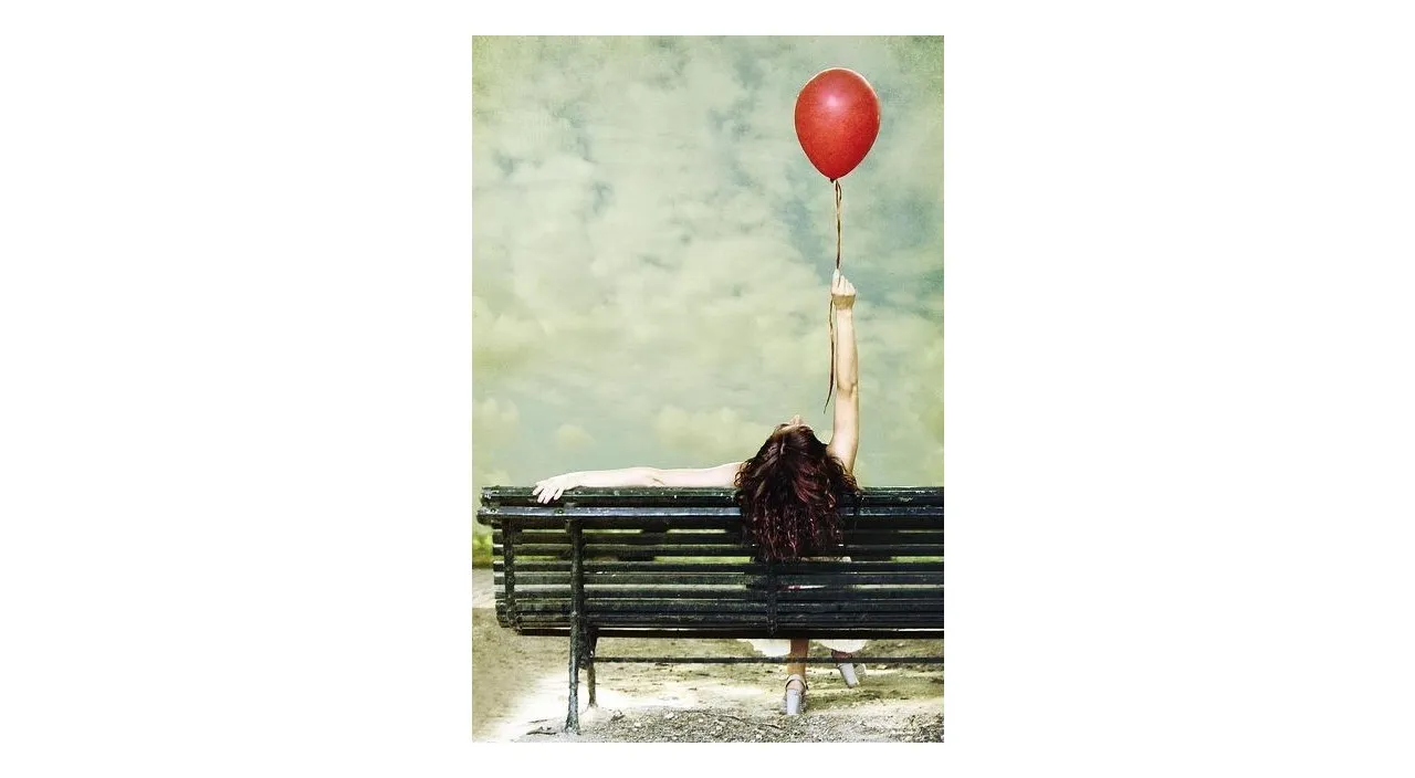 a woman laying on a bench with a red balloon