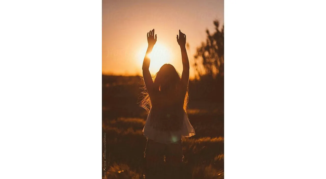 a woman standing in a field with her arms in the air