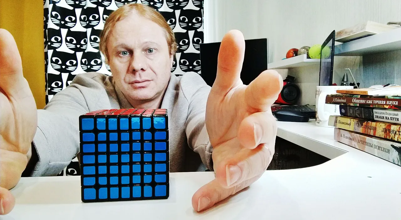 a man sitting at a table with a rubik cube in front of him