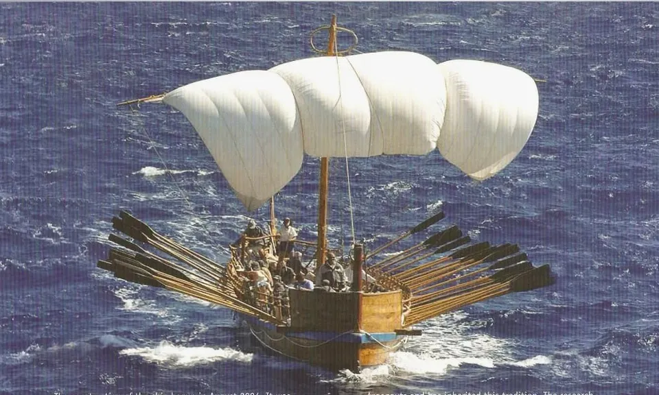 a sailboat with white sails in the ocean