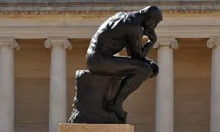 a statue of a man sitting in front of a building