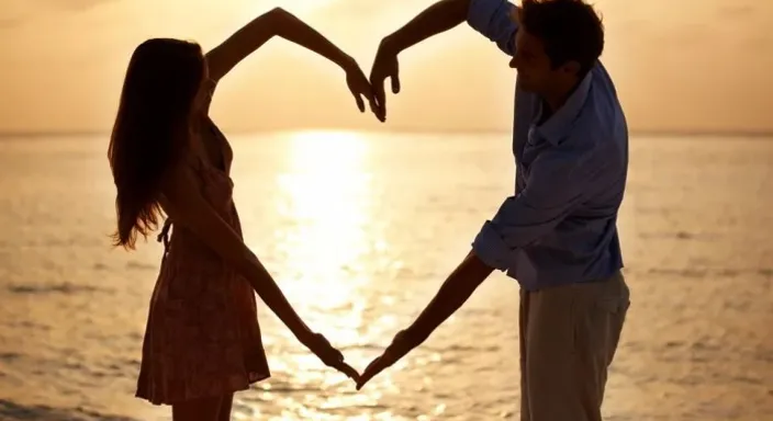 a man and a woman holding hands while standing on a beach