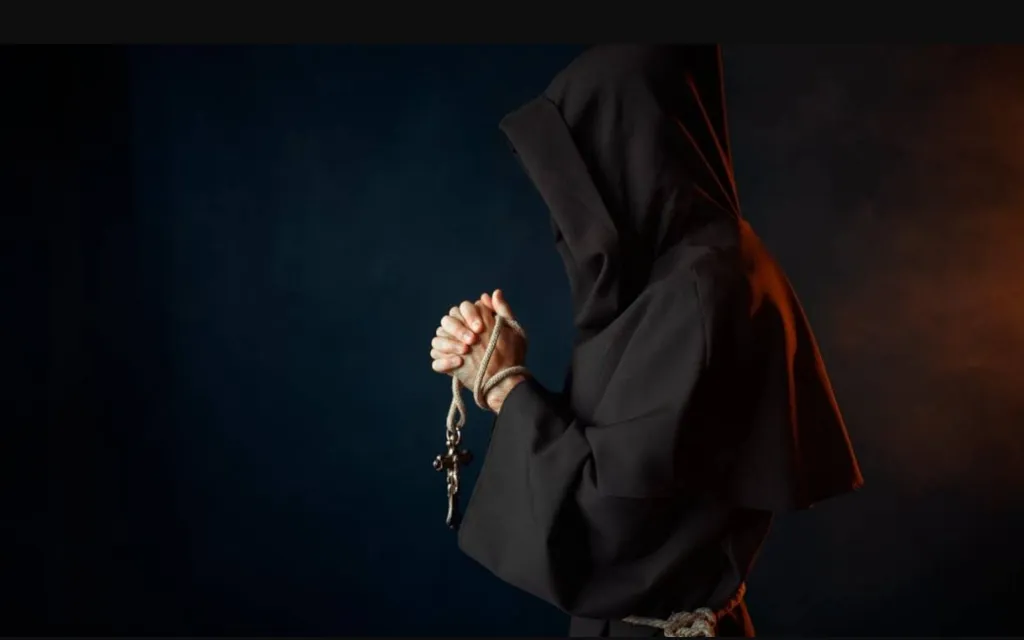 a woman in a black hoodie holding a rosary