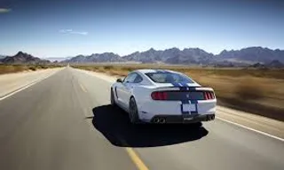 a white sports car driving down a desert road