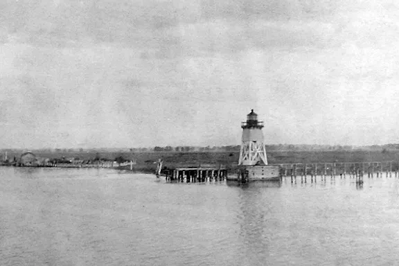 a black and white photo of a lighthouse in the water