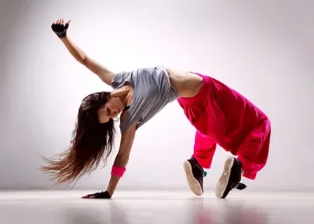 A woman doing a dance move in a studio with neon colors setting the room on chromatic blaze