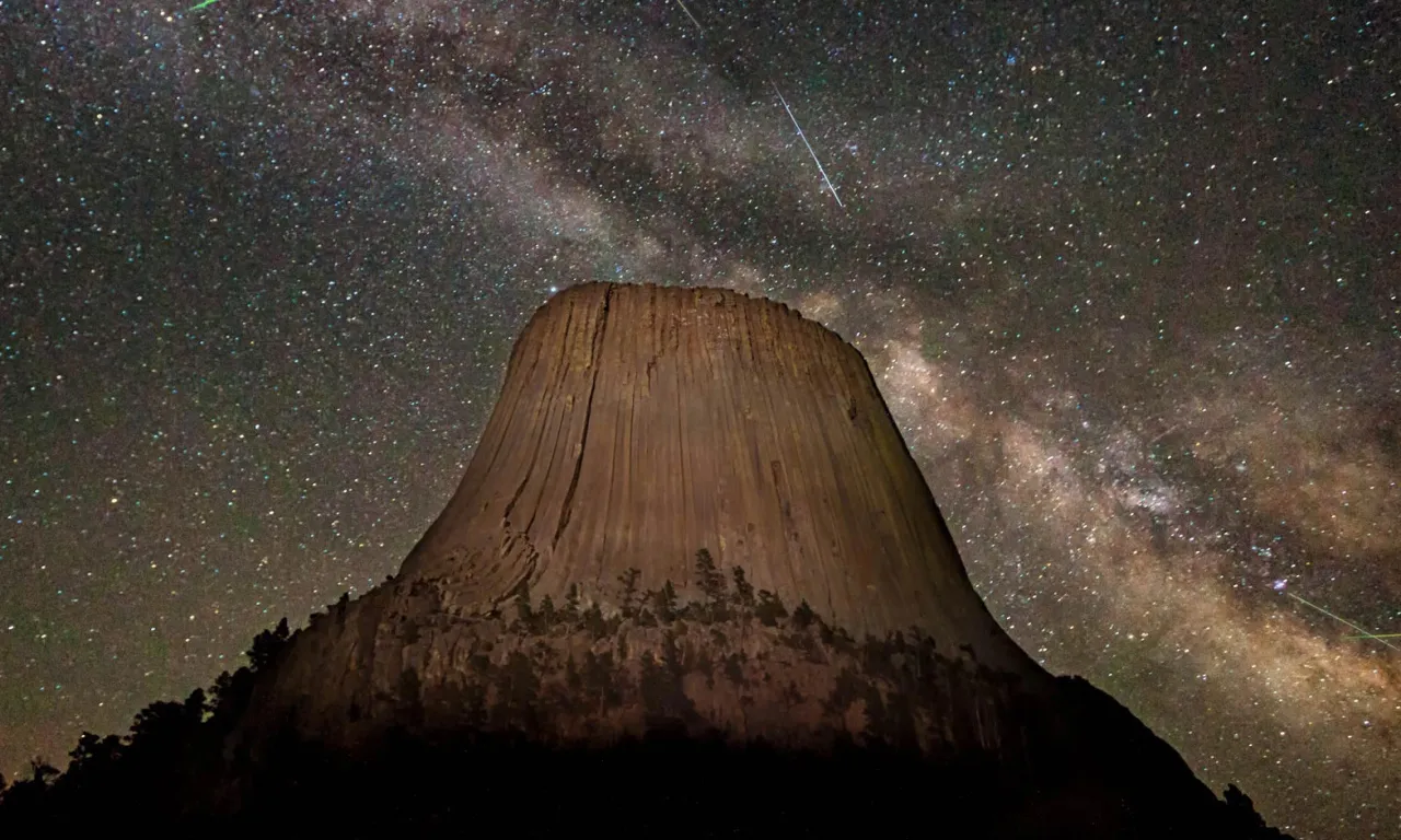 the night sky with stars above a mountain