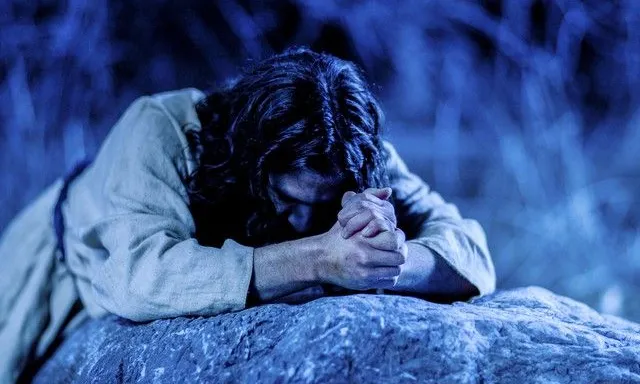 a man laying on a rock with his hands clasped