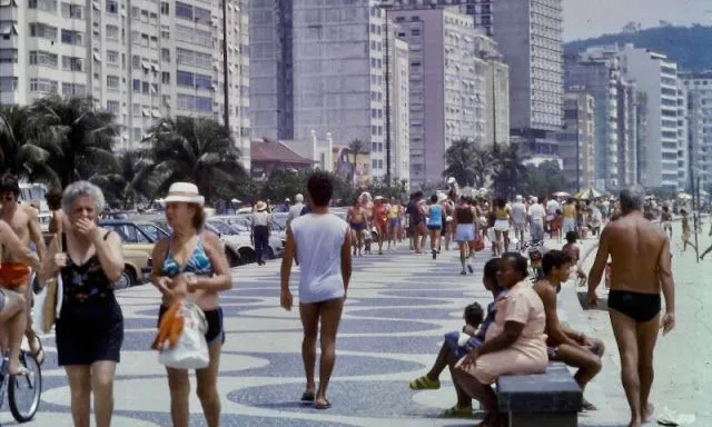 a group of people walking down a street next to tall buildings