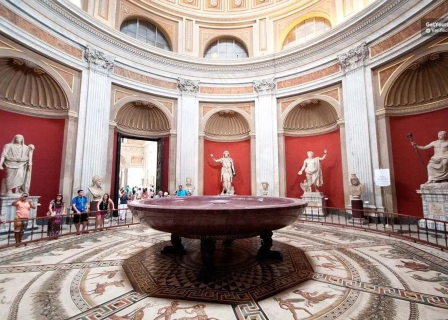 a large room with statues and a maroon bathtub