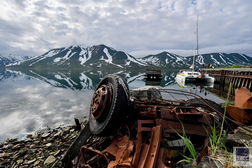 a rusted out boat sitting on the shore of a lake