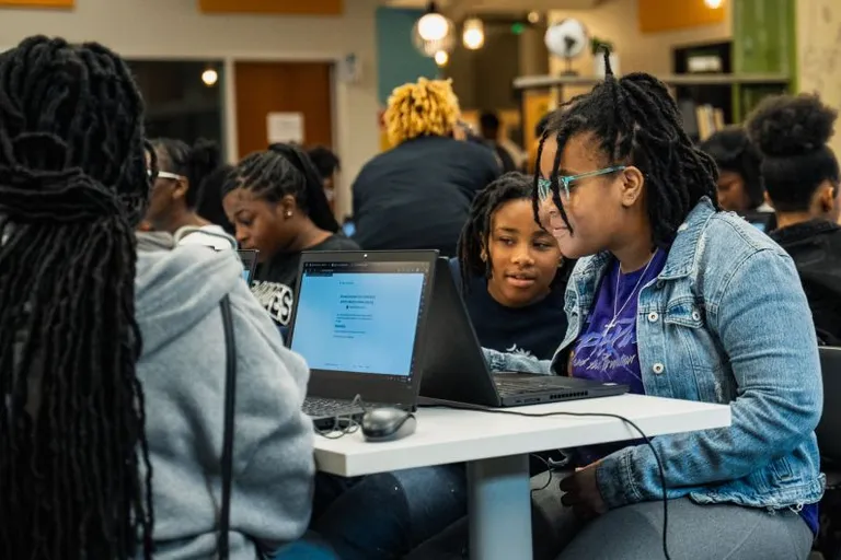 a group of people sitting at a table with laptops