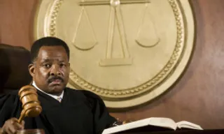 indian judge sitting at a desk with a gavel in front of him 