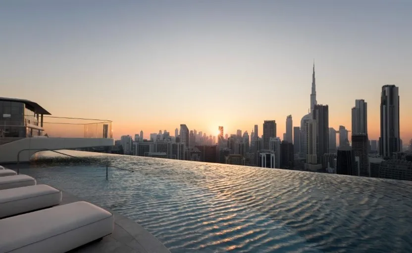 a swimming pool overlooking a city skyline at sunset