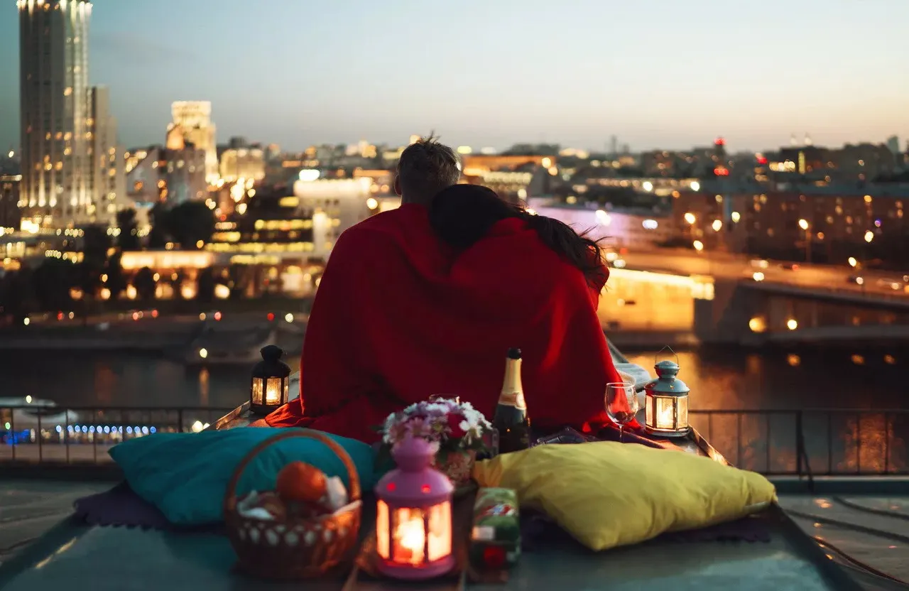 a person sitting on a ledge overlooking a city at night