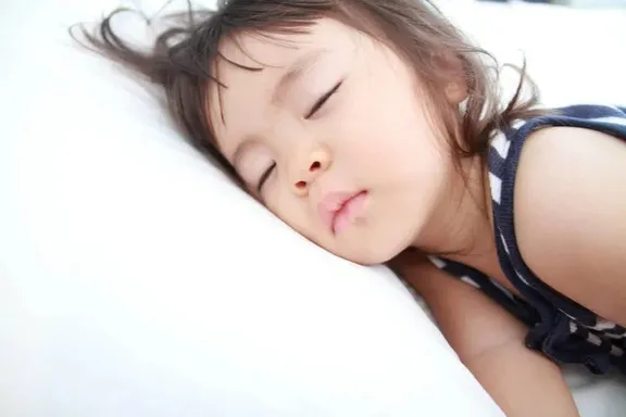 a little girl sleeping on a bed with her eyes closed