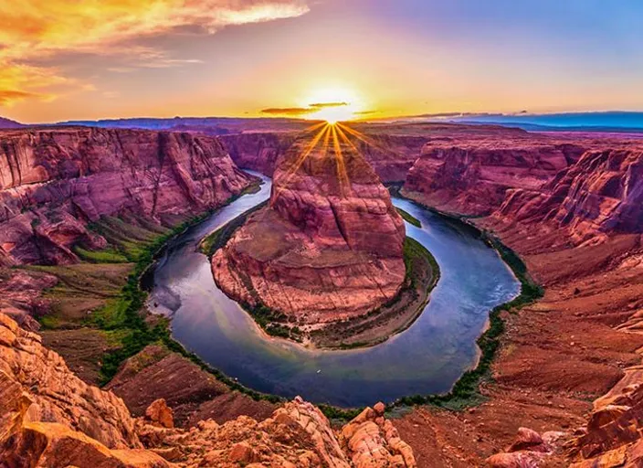 the sun is setting over a river in a canyon