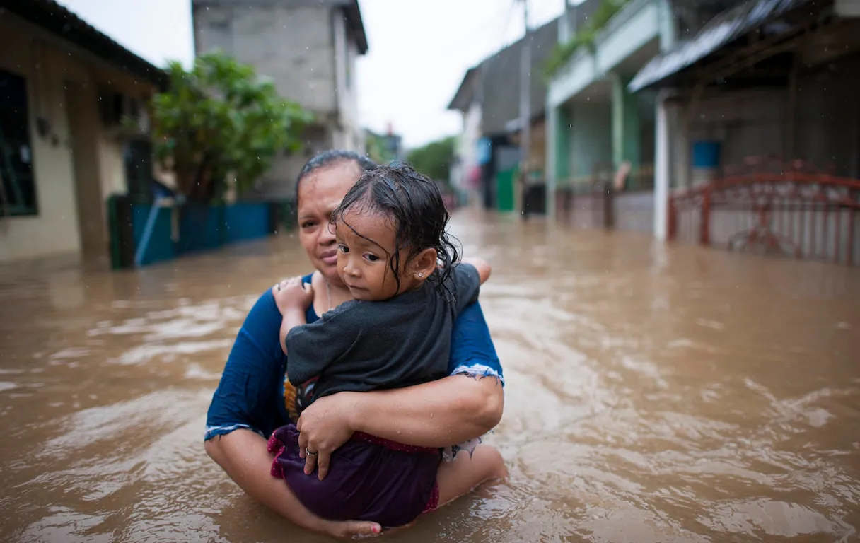 a woman holding a child in a flooded street