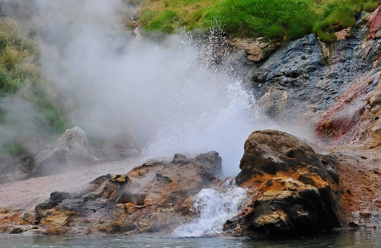 a geyser spewing out water into a body of water