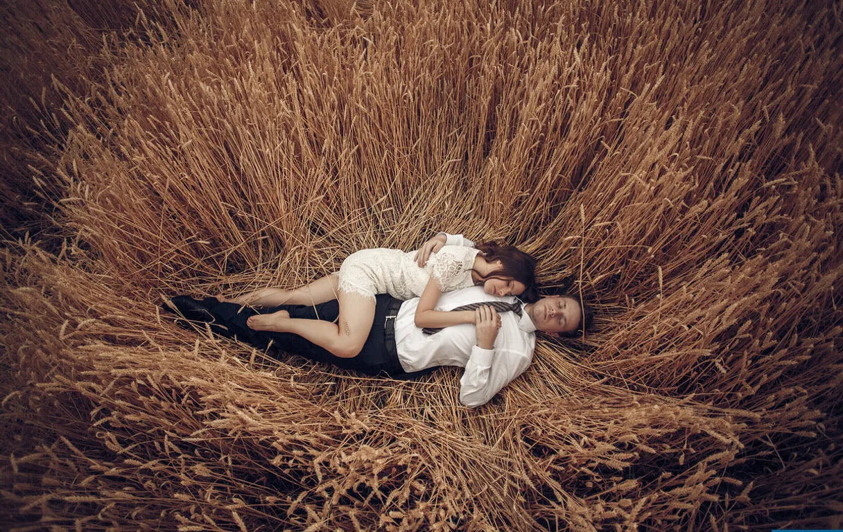 a man and a woman laying in a field of hay