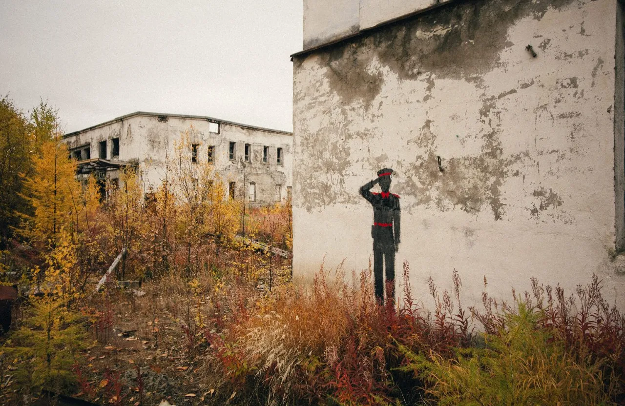 a man standing in front of a wall with a painting on it