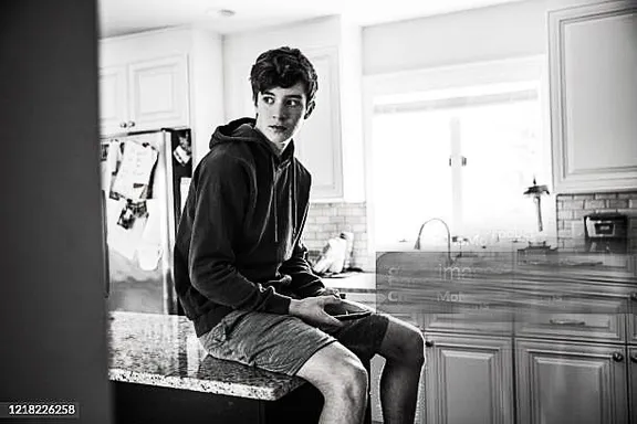 a man sitting on top of a counter in a kitchen