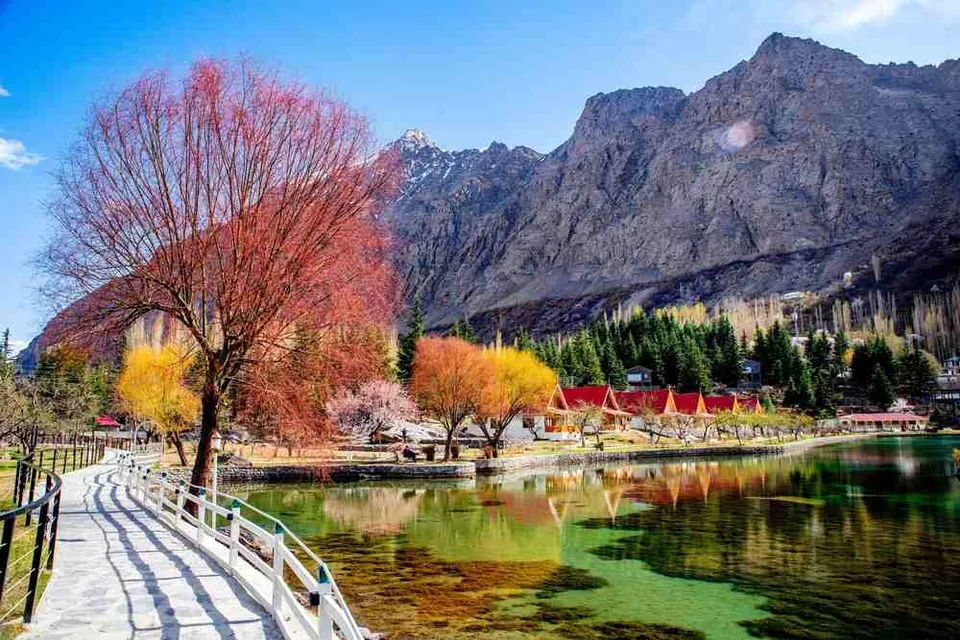 a wooden walkway leading to a lake surrounded by mountains