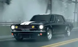 a black car driving down a road next to a forest