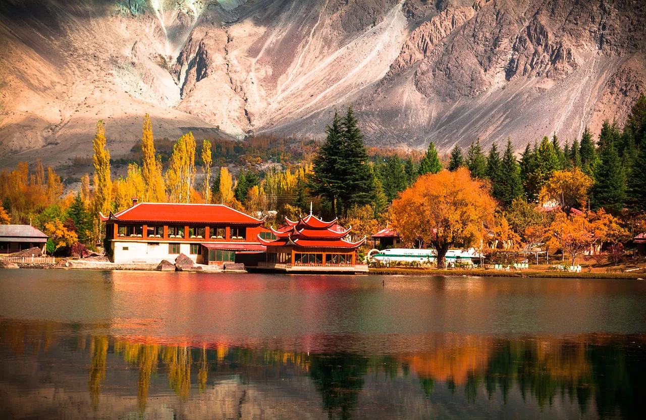 a lake surrounded by mountains with a red roof