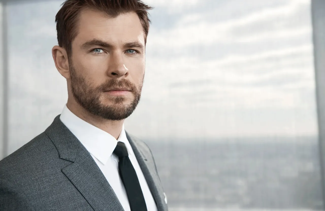 a man in a suit and tie standing in front of a window