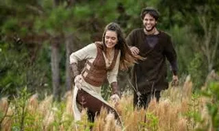 a man and a woman walking through tall grass