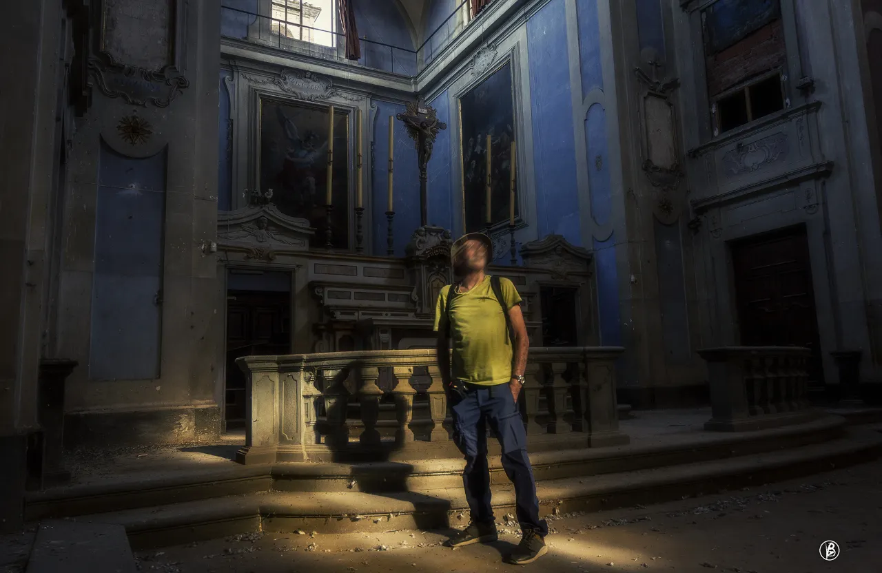 a man in a yellow shirt standing in a dark room