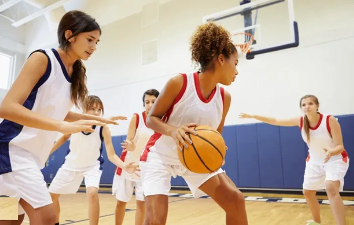 a group of young women playing a game of basketball