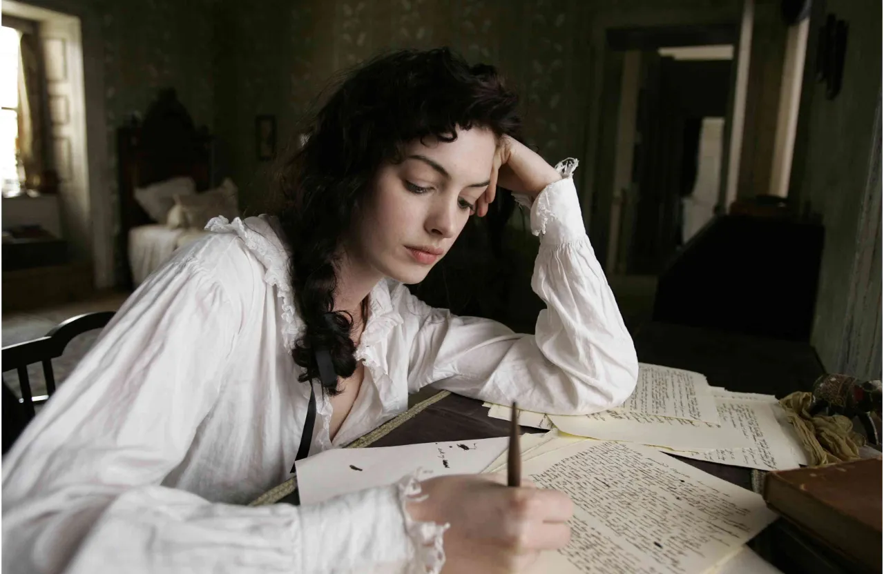 a woman sitting at a table with a book and pen