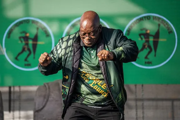 a zulu bald man in a green shirt is dancing doing a jig.