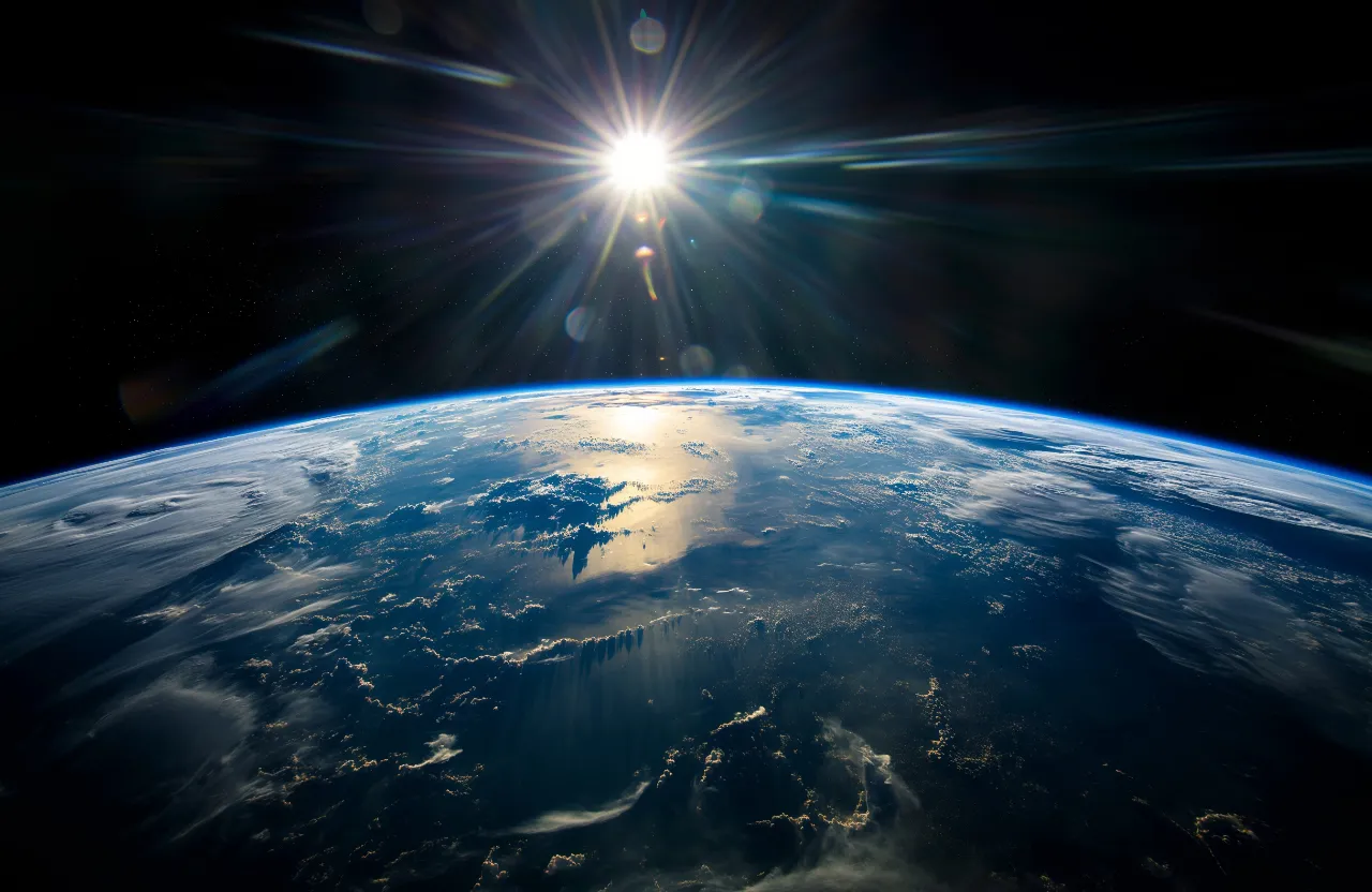 the sun shining over the earth from space