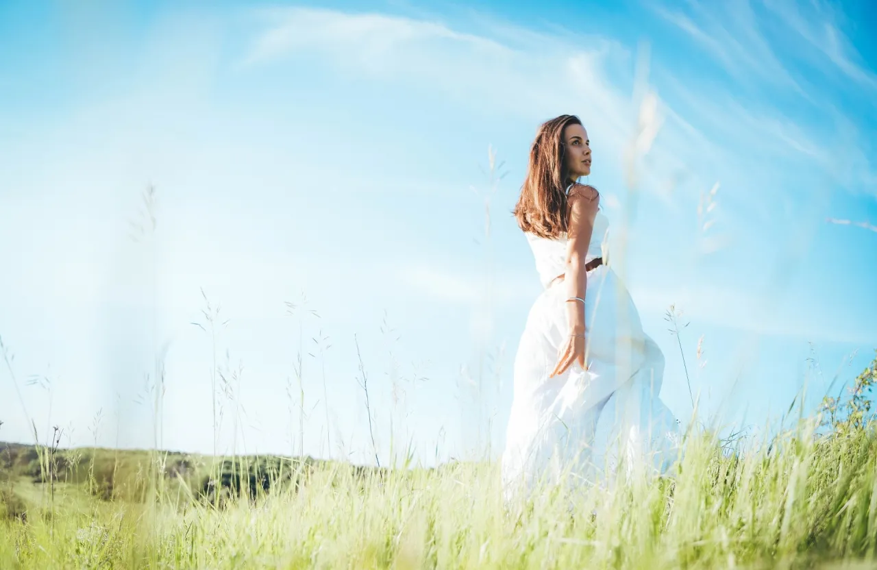 a woman in a white dress standing in a field