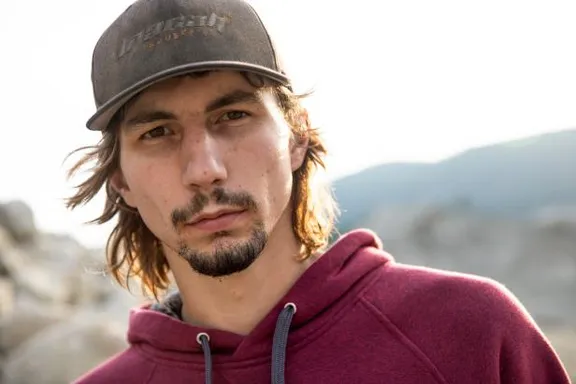 a man with long hair wearing a hat