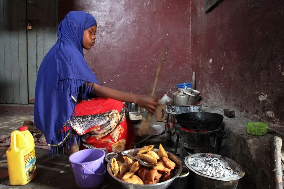 inside of a small poor man's African hut with low height, with a few utensils, a 30 year old woman cooking