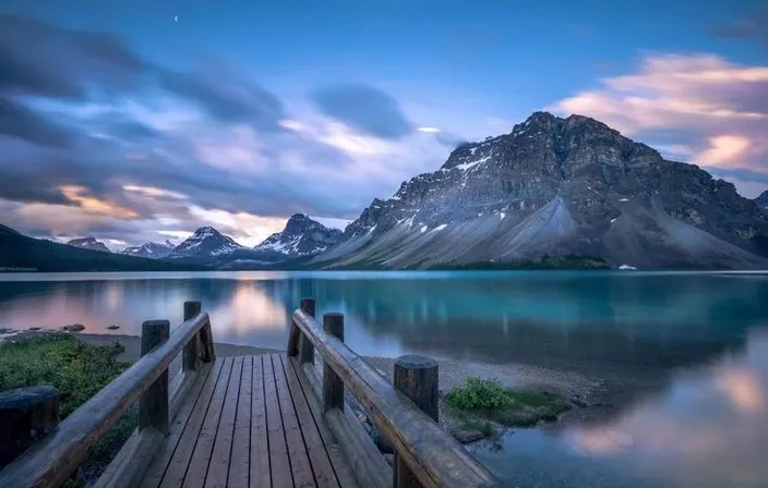 a wooden dock sitting on top of a lake under a cloudy sky