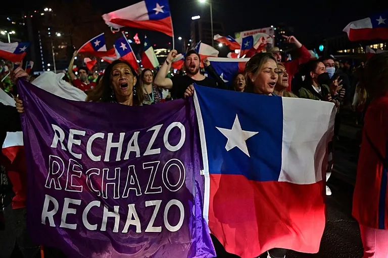 a large group of people holding chile flags and singing